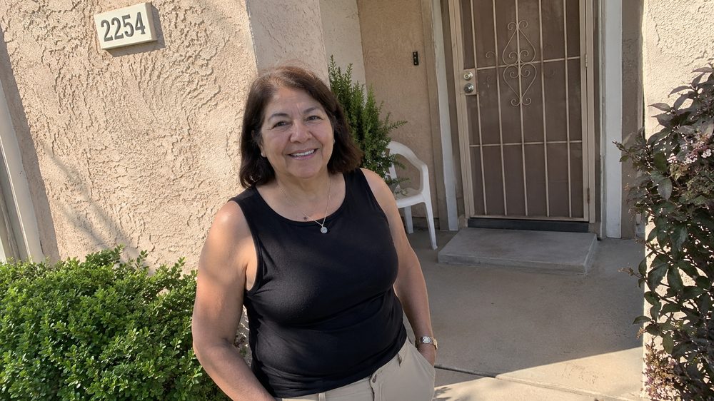 Rosa Delgado, a member of the cleaning crew, standing outside a house in the sun